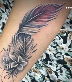 a feather and flower tattoo on the leg