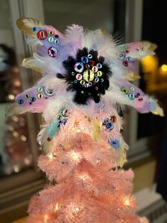 a pink christmas tree decorated with feathers and beads