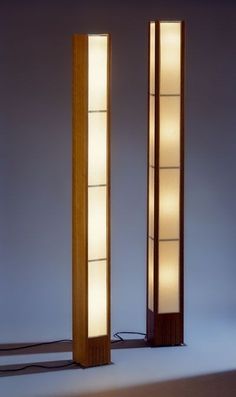 two tall wooden lamps sitting next to each other on top of a white flooring