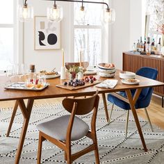 a dining room table is set with plates and glasses on it, next to a blue chair