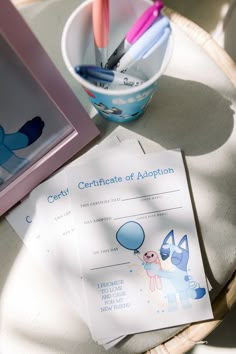 two certificates sitting on top of a table next to a cup