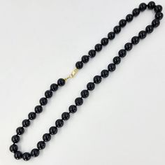 This onyx bead necklace features 8mm black onyx beads measuring 16 inches in length and with a 14 Karat yellow gold clasp. Classic Black Round Beaded Jewelry, Black Onyx 8mm Bead Jewelry, Black Onyx 8mm Beads Jewelry, Black Onyx Jewelry With 8mm Beads, Classic Onyx Jewelry With Gemstone Beads, Classic Onyx Round Bead Jewelry, Classic Onyx Round Beads Jewelry, Black Beaded Necklaces With Lobster Clasp, Classic Black Beaded Necklaces With Polished Beads