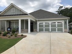 a gray house with white pillars and two garages