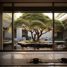 a bonsai tree is seen through an open window in a japanese style room with two tea cups on the table