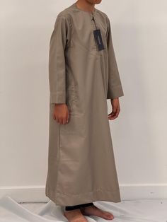 Introducing our Boys Hadi thobe, the perfect addition to your young ones Islamic clothing collection. Made from a high-quality cotton mix fabric, this thobe is not only easy to iron but also incredibly soft and comfortable to wear. The meticulous stitching and expert embroidery make this thobe a truly stand-out piece. Available in a wide range of colours and sizes, you're sure to find the perfect fit for your personal style. We also offer this Hadi thobe in Men's sizes. Whether you're attending Casual Cotton Long-sleeved Thobe, Casual Cotton Thobe With Long Sleeves, Casual Long-sleeved Cotton Thobe, Casual Long Sleeve Cotton Thobe, Casual Cotton Thobe For Eid, Beige Long Sleeve Cotton Kaftan, Islamic Clothing, Mixing Fabrics, Everyday Wardrobe