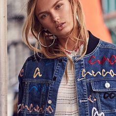 a woman wearing a jean jacket and hoop earrings