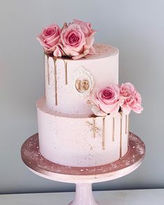 a three tiered cake with pink flowers on top and gold foiling around the edges