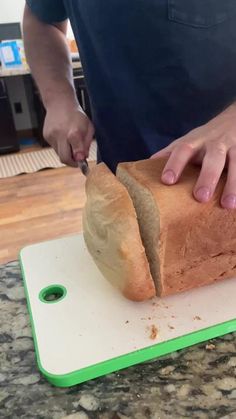 a person cutting up a loaf of bread on top of a cutting board with a knife