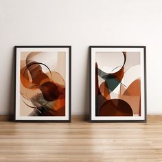 two framed art prints sitting on top of a wooden table