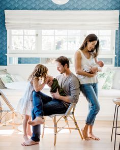 a woman holding a baby sitting on top of a chair next to two other people