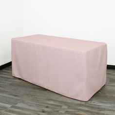 a pink table cover sitting on top of a hard wood floor next to a white wall