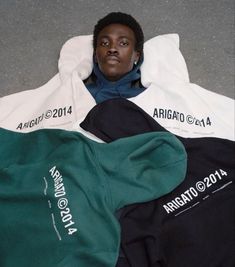 a man laying on the ground next to two shirts that are green, white and black