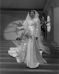 an old photo of a woman in a wedding dress standing on the steps with her bouquet