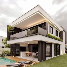 a modern house with a pool and deck chairs on the grass next to it's patio