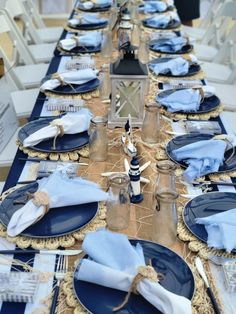 the table is set with blue plates and place settings for an elegant dinner or party