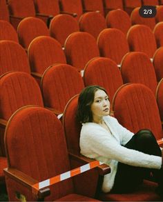 a woman is sitting in an empty auditorium