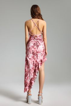 the back of a woman wearing a pink dress with floral print on it and high heels