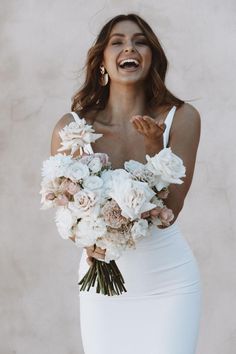 a woman in a white dress holding a bouquet of flowers with her mouth wide open