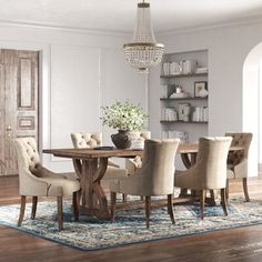 a dining room table with chairs and a chandelier hanging from it's ceiling