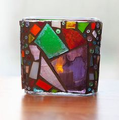 a colorful glass vase sitting on top of a wooden table