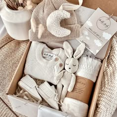 a box filled with baby items sitting on top of a bed next to a potted plant