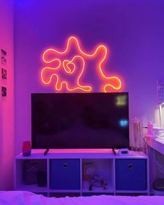 a television sitting on top of a tv stand in a bedroom next to a neon sign