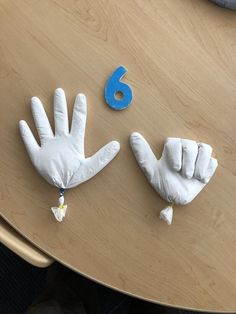 two white gloves with blue numbers on them sitting on a table next to a pair of hands