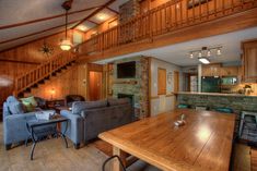 a living room filled with furniture next to a wooden table and staircase leading up to a loft