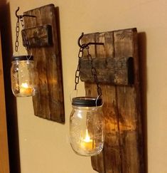 two mason jars are hanging from the wall with candles in them and one is filled with water