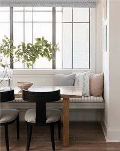 a table with two chairs and a bench in front of a window next to a potted plant