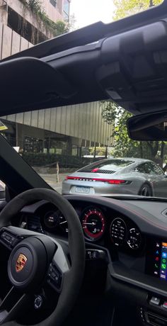 the interior of a car with dashboard lights and steering wheel controls in front of a building