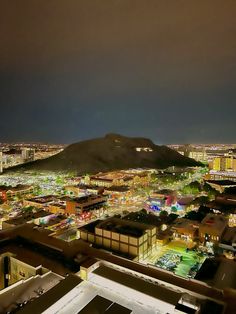 an aerial view of a city at night with the lights on and mountains in the background