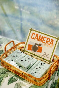 a wicker basket with some cards in it and a camera sitting on the table