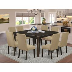 a dining room table with beige chairs and an area rug in front of the kitchen