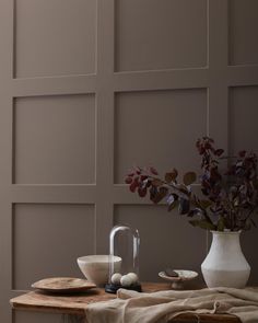 a table with plates, bowls and vases on it in front of a wall