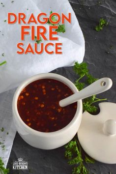 a bowl of dragon fire sauce next to a spoon and napkin on a black surface