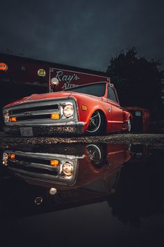 an orange truck parked in front of a building with its hood up and lights on