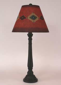 a lamp with a red shade on it sitting next to a white wall and floor