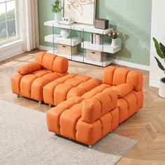 an orange sectional sofa sitting on top of a hard wood floor next to a window