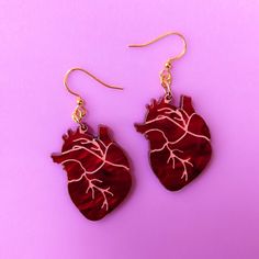 "Edgy anatomical heart earrings! Our gold finished stainless-steel earring hooks are nickel free so you can rock these cuties comfortably - even if you're sensitive! Great if you're looking to add something fun to your style! Charm is made from 1/8\" red pearl acrylic that is cut and painted in our home studio. Item is packaged in a compostable cellulose bag and is shipped plastic free." Red Pearl, Anatomical Heart, Earring Hooks, Acrylic Earrings, Stainless Steel Earrings, Home Studio, Heart Earrings, Plastic Free, Our Home