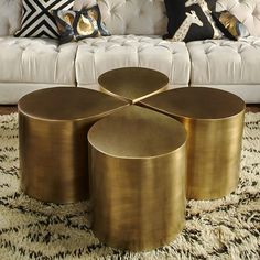 a living room filled with white couches and gold tables on top of a rug