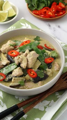 a white bowl filled with chicken and veggies on top of a green table cloth