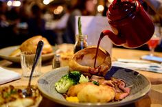 a person pours sauce over a plate of food