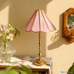 a pink lamp sitting on top of a table next to a vase filled with flowers