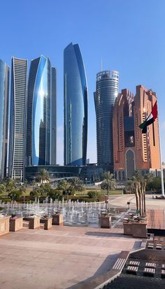 several tall buildings in the middle of a city with fountains and palm trees around them