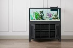 a fish tank sitting on top of a black cabinet next to a wall with white paneling