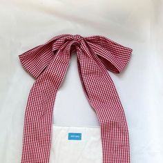 a red and white checkered scarf with a blue tag hanging from it's side