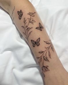 a woman's arm with butterflies on it and flowers in the middle of her arm