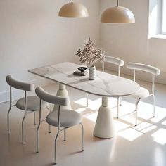 a white table with four chairs and a vase filled with flowers on top of it