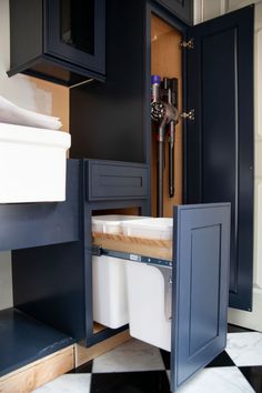 an open cabinet door in a kitchen with black cabinets and white checkered flooring